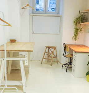 Photo of the smaller personal sewing studio with cutting table, clothes rag and working table.